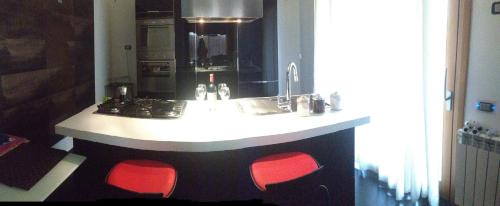 卡利亞里的住宿－Alex House，厨房周围设有红色椅子和柜台