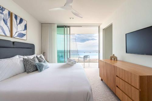 a bedroom with a large bed and a flat screen tv at Monet by Khove - Kirra Beach in Gold Coast