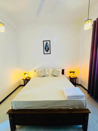 a bedroom with a large bed with two side tables at Villa Vows in Tangalle