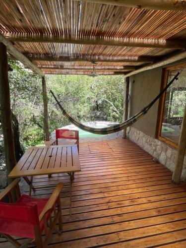 a porch with a hammock and a table and chairs at Descansa al pie del champaqui escuchando el arroyo in San Javier