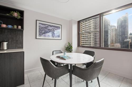 un comedor con una mesa y sillas blancas y una ventana en City Escape with Spa Access in Darlinghurst, en Sídney