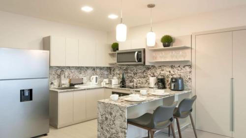 a kitchen with a counter with chairs and a refrigerator at Modern 1-Bedroom with Park Views in Panama City in Panama City