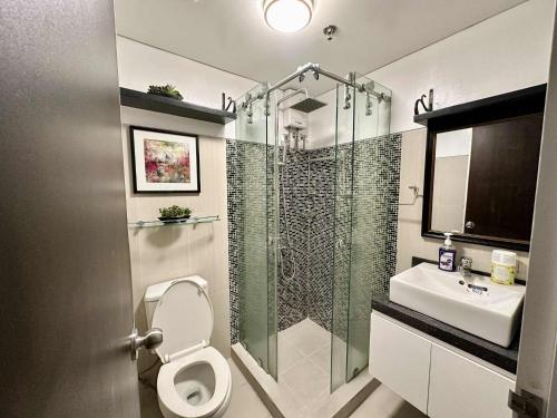 a bathroom with a shower and a toilet and a sink at Shell Residence 2 bedroom by Kathy in Manila