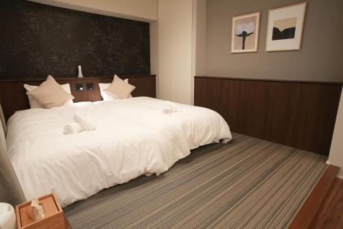 a bedroom with a large bed with white sheets at SOULEIADO Shinosaka in Osaka