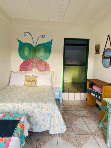 een slaapkamer met een bed met een vlinder aan de muur bij Casinha hibisco in Conceição da Ibitipoca