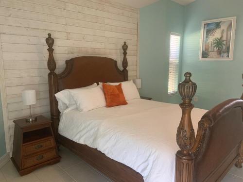una camera da letto con un letto con lenzuola bianche e cuscini arancioni di Sunsets Waterfront Saltwater Heated Pool Retreat a Punta Gorda
