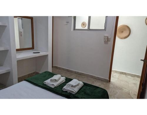 une salle de bain avec deux serviettes sur un lit avec un miroir dans l'établissement Villa Caracol - Hello Progreso, à San Benito