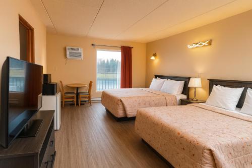 a hotel room with two beds and a flat screen tv at Motel St-Eustache in Saint-Eustache