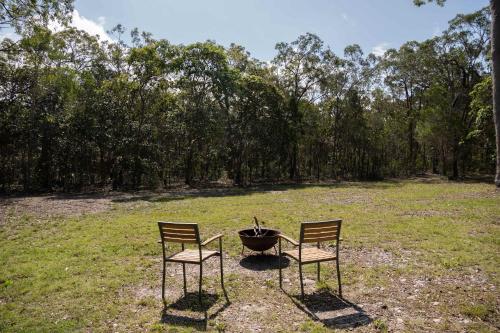 two chairs and a fire pit in a field at Bush by the Bay by Tiny Away in River Heads