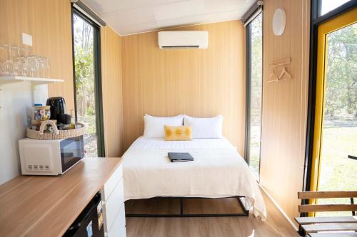 a bedroom with a bed and a desk with a tv at Bush by the Bay by Tiny Away in River Heads