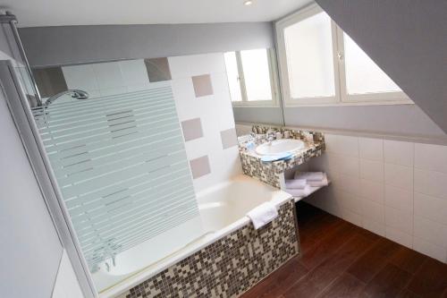 a bathroom with a shower and a tub and a sink at Hôtel Europe and Spa in Reims