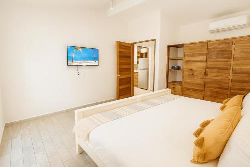 Un dormitorio con una cama blanca y un televisor en la pared. en Boho Minimal 3-Min Beach Private Parking, en Puerto Aventuras