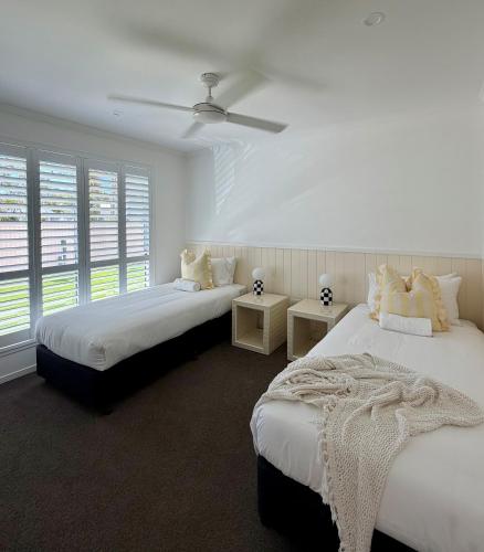 a white room with two beds and a window at The Little Tropicana in Byron Bay