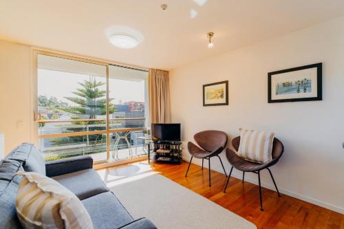 a living room with a couch and chairs and a tv at Sumner Bay Motel in Christchurch