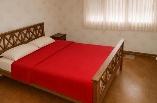 Chalet en Miramar, para 5 personas في ميرامار: غرفة نوم بها سرير كبير وبطانية حمراء