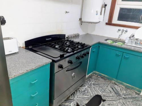 Chalet en Miramar, para 5 personas في ميرامار: مطبخ مع موقد ودواليب زرقاء