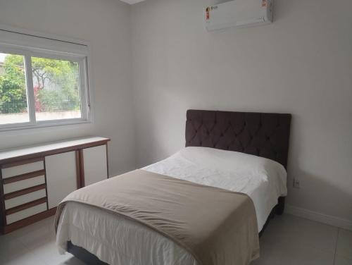 une chambre avec un grand lit et une fenêtre dans l'établissement Casa para Veraneio em Torres, à Torres