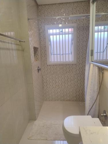 a bathroom with a shower and a toilet and a window at Casa para Veraneio em Torres in Torres