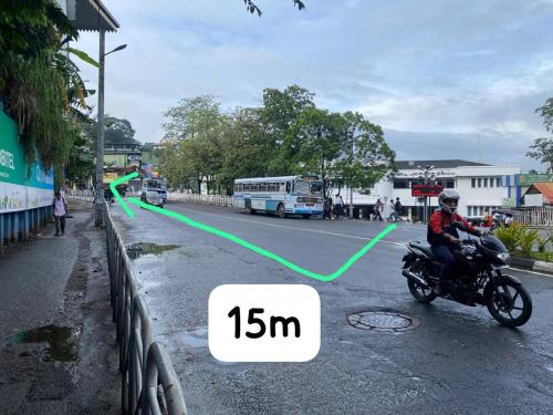 a man riding a motorcycle down a street at Kandy Railway Inn in Kandy