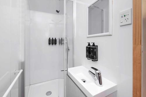 a white bathroom with a sink and a shower at Queenstown Top 10 Holiday Park in Queenstown