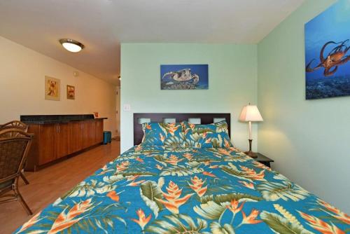 a bedroom with a bed with a blue and orange bedspread at Kaleialoha 402 · KA 402 Spacious Studio Close to Ocean Heated Po in Kahana