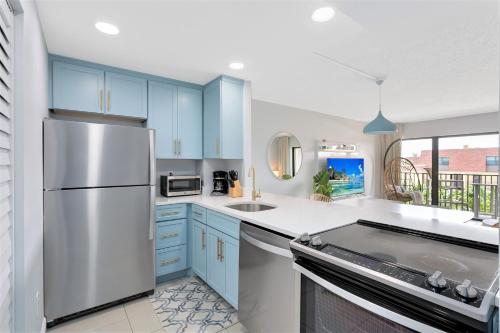 a kitchen with blue cabinets and a stainless steel refrigerator at Chateau by the Sea in Cocoa Beach