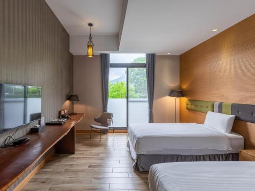 a hotel room with two beds and a desk at Hualien Toongmao Resort in Jian