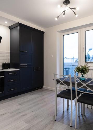 a kitchen with black cabinets and a dining table at LuxCity Apartment in the Center of Nowy Targ, FREE PARKING in Nowy Targ