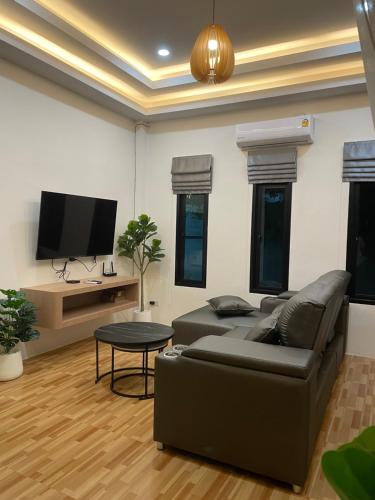 a living room with a couch and a tv at LOMA Pool Villa in Ban Nong Thale