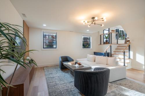 a living room with a white couch and chairs at Modern Entire Home Near UVA in Charlottesville