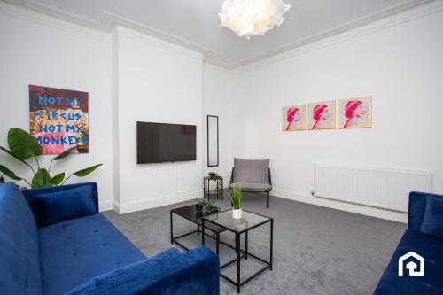 a living room with a blue couch and a tv at Vacant Nests The Fredrick Close to sea front in Seaham