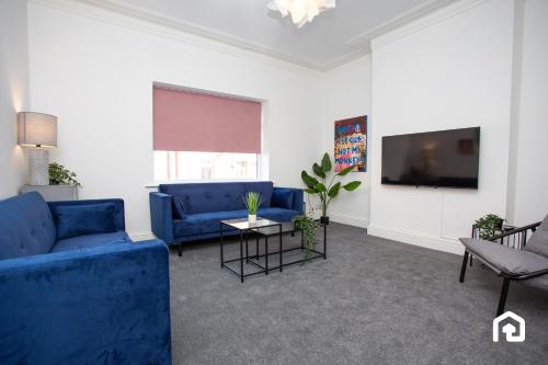 a living room with blue couches and a tv at Vacant Nests The Fredrick Close to sea front in Seaham