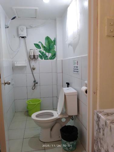 a bathroom with a toilet and a green trash can at Lola Flor's Guest House in El Nido