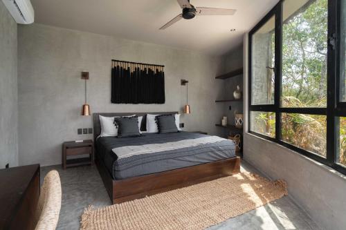 a bedroom with a bed and a large window at Esencia Villas Tulum Priv Pool Concierge in Tulum