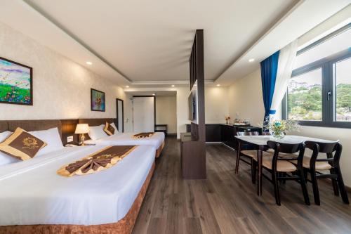 ein Hotelzimmer mit einem großen Bett und einem Tisch in der Unterkunft ROYAL DRAGON HOTEL in Da Lat