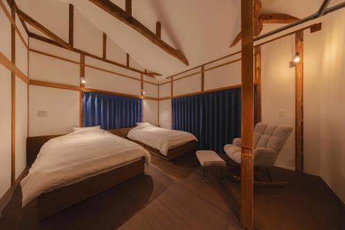 a bedroom with two beds and a chair in it at 鎌倉とばり - 最大6名でゆったり過ごせる宿 in Kamakura