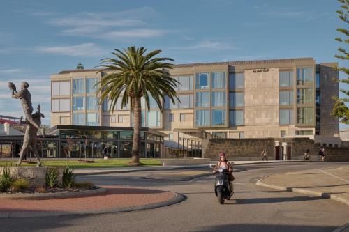 a person riding a bike down a street in front of a building at Garde and Warders Hotel in Fremantle