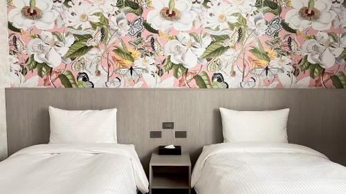 two beds with white sheets and a floral wall mural at 星雨行館-逢甲洲際館 in Taichung