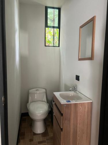 a bathroom with a toilet and a sink and a window at Live bambu in Caimital