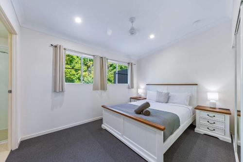 una camera da letto bianca con un letto e due finestre di Tropical Resort Apartment a Cannonvale