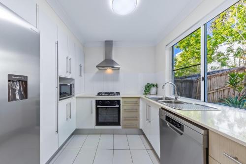 una cucina con mobili bianchi e una grande finestra di Tropical Resort Apartment a Cannonvale