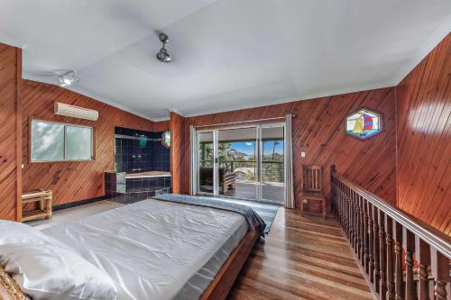 a bedroom with a bed in a room with wooden walls at Treetop Paradise Retreat with Pool in Cannonvale