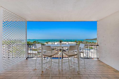 a table and chairs on a balcony with a view of the ocean at Ocean View Studio 14A KIDS STAY FREE in Airlie Beach