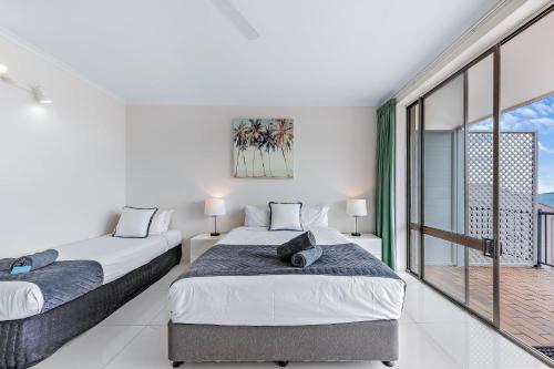two beds in a room with a balcony at Central Ocean View Studio 27a in Airlie Beach