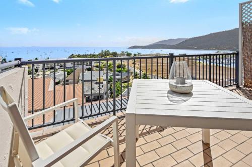 a white table and chairs on a balcony with the ocean at Ocean View Apartment 27 in Airlie Beach