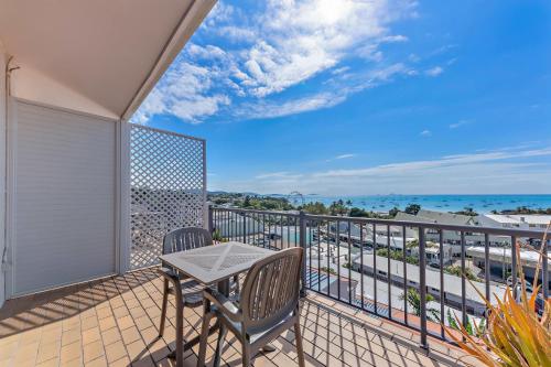 a balcony with a table and chairs and the ocean at OCEAN VIEWS 10A in Airlie Beach