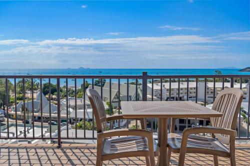 Una mesa y sillas en un balcón con vista al mar. en OCEAN VIEWS 10A, en Airlie Beach