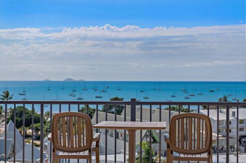 a table and chairs on a balcony with a view of the ocean at OCEAN VIEWS 10 in Airlie Beach