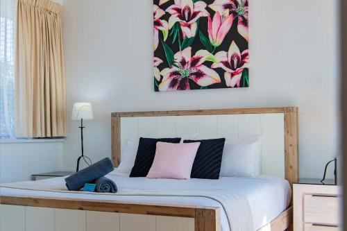 a bedroom with a bed with a painting on the wall at OCEAN VIEWS 10 in Airlie Beach