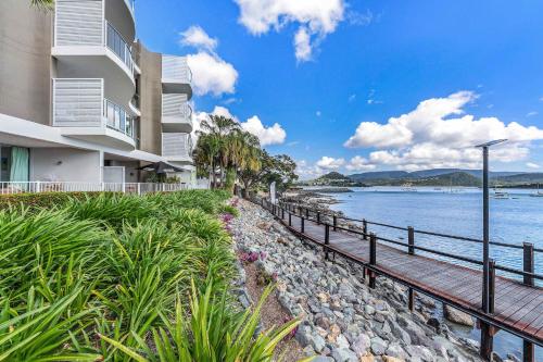 a building with a walkway next to a body of water at By The Sea Shore With Pool in Airlie Beach